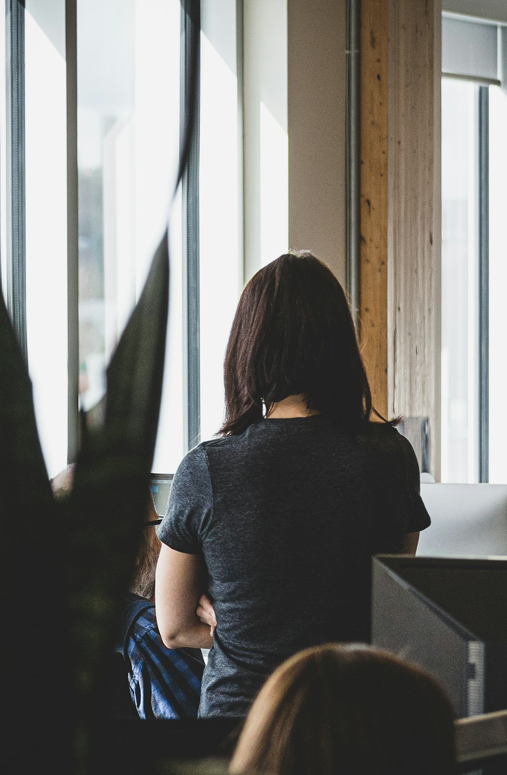 woman in gray shirt standing near window