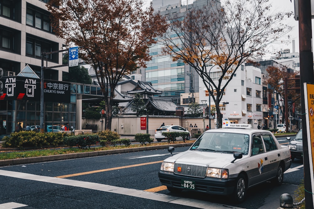 a white taxi cab driving down a street next to tall buildings