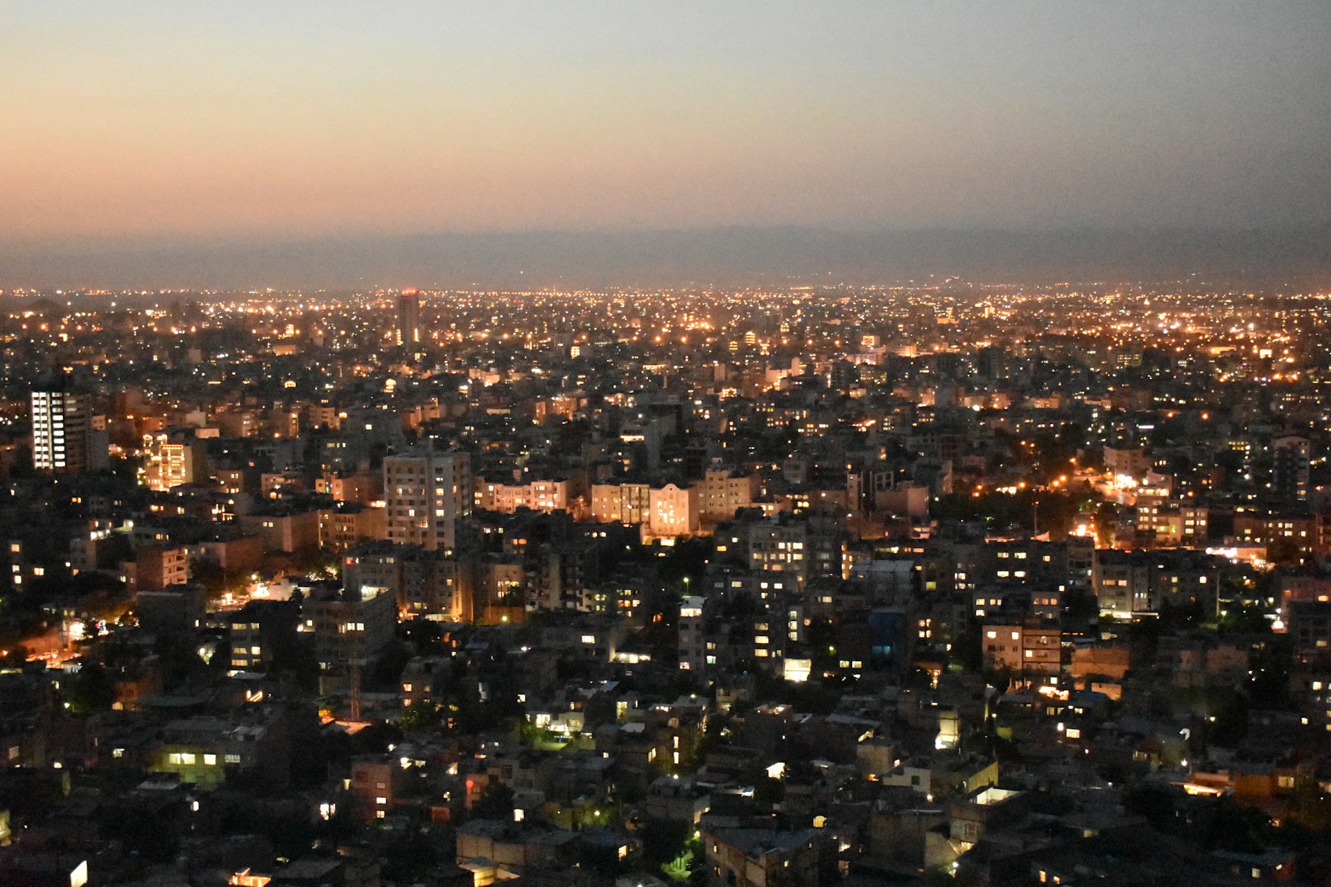 A vibrant cityscape at twilight, alive with glowing lights and bustling streets.