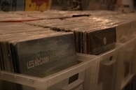 Stacks of vinyl records leaning against a shadowed wall, hinting at music’s tactile presence.