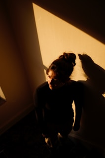 A dramatic shot of a woman lounging in a dimly lit room, her form partially obscured by shadows.