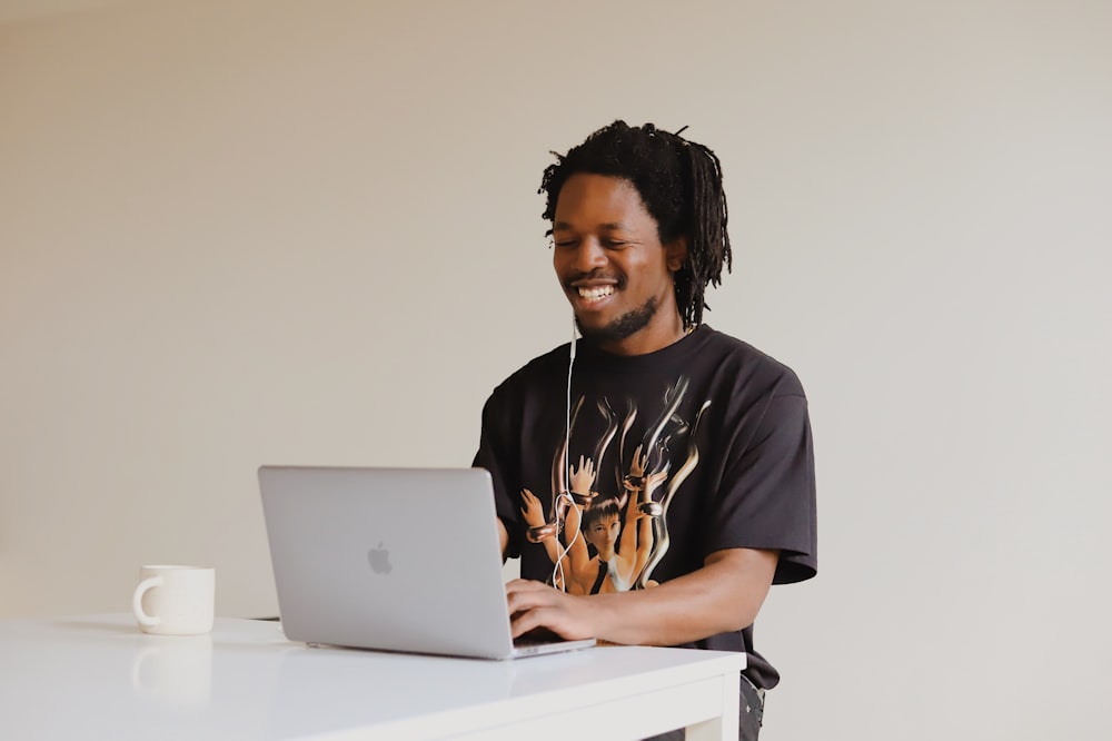 黒のクルーネックTシャツを着た男(MacBookを使用)