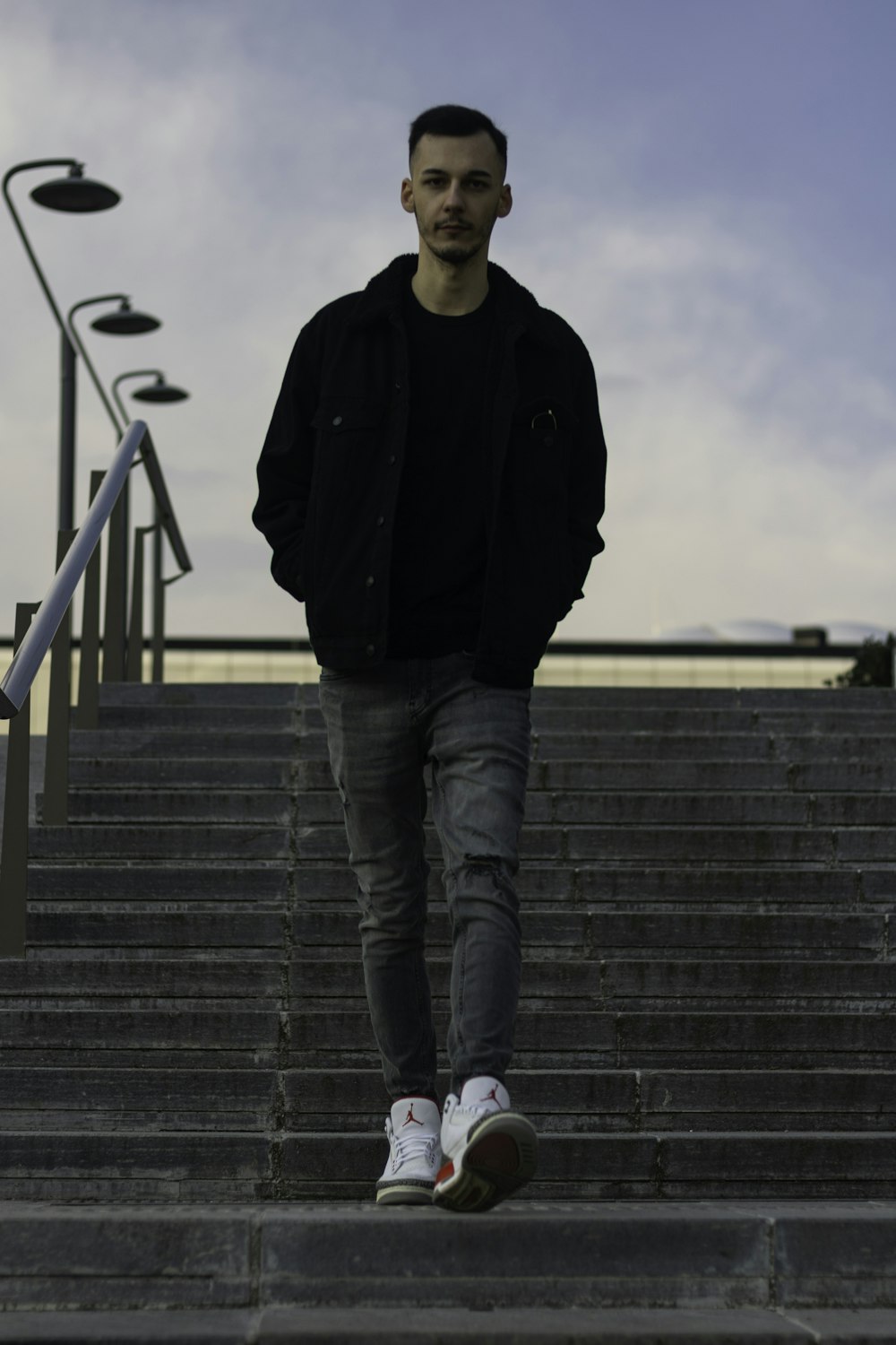 Foto hombre con chaqueta negra y jeans azules parados en las escaleras –  Imagen Mi gratis en Unsplash