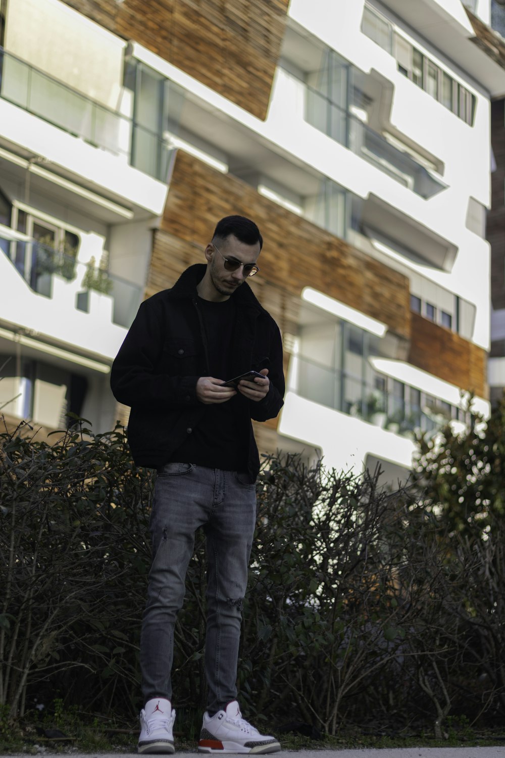 man in black jacket standing near green plant during daytime