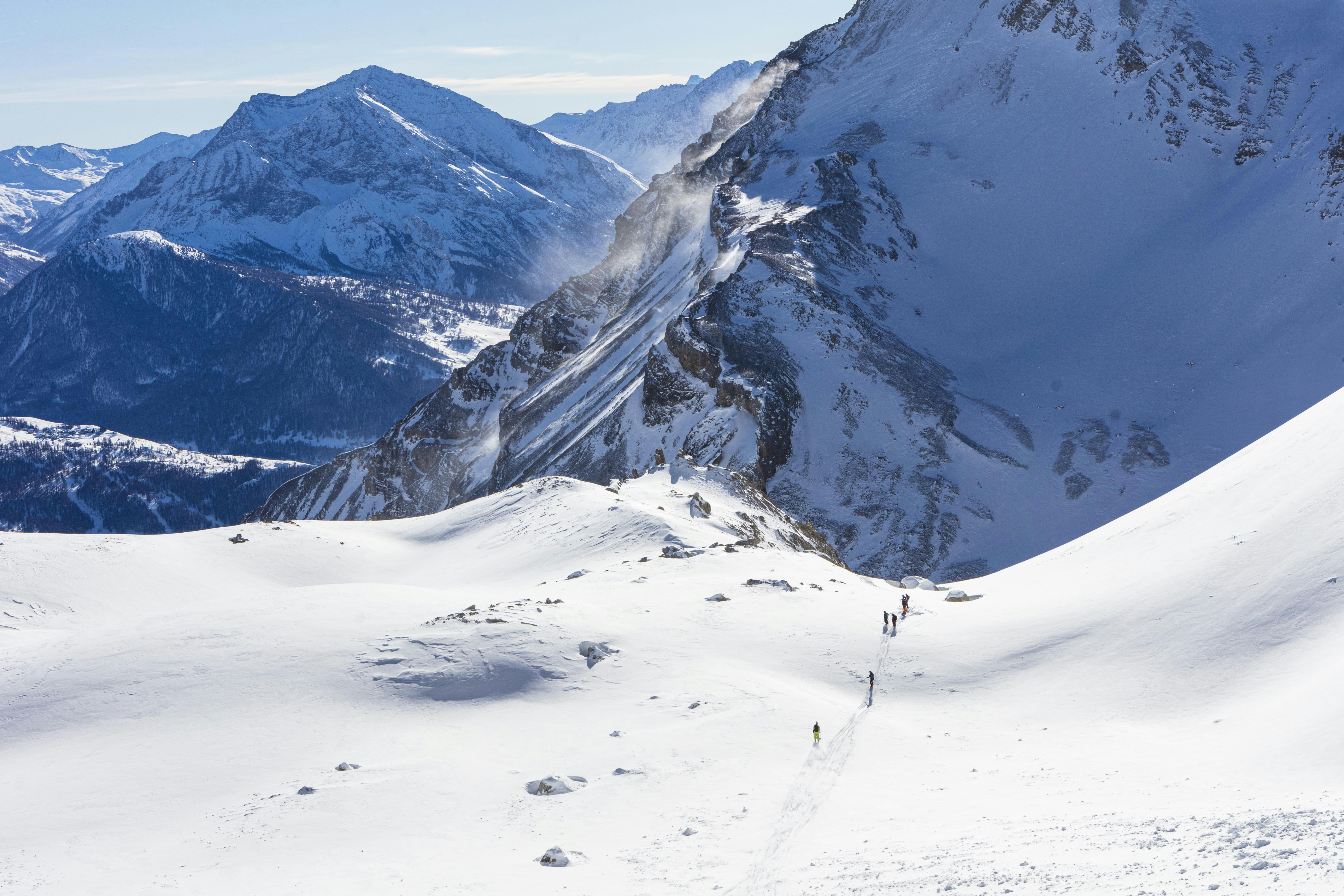 snow covered mountain during daytime, A group of skiers descends Mount Chaberton crossing over from the Italian side near Sestriere into the French side near the ski resort of Montgenèvre