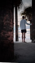 Guests walking barefoot along a sandy path lined with palm trees.