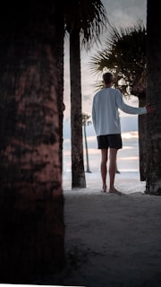 Guests walking barefoot along a sandy path lined with palm trees.