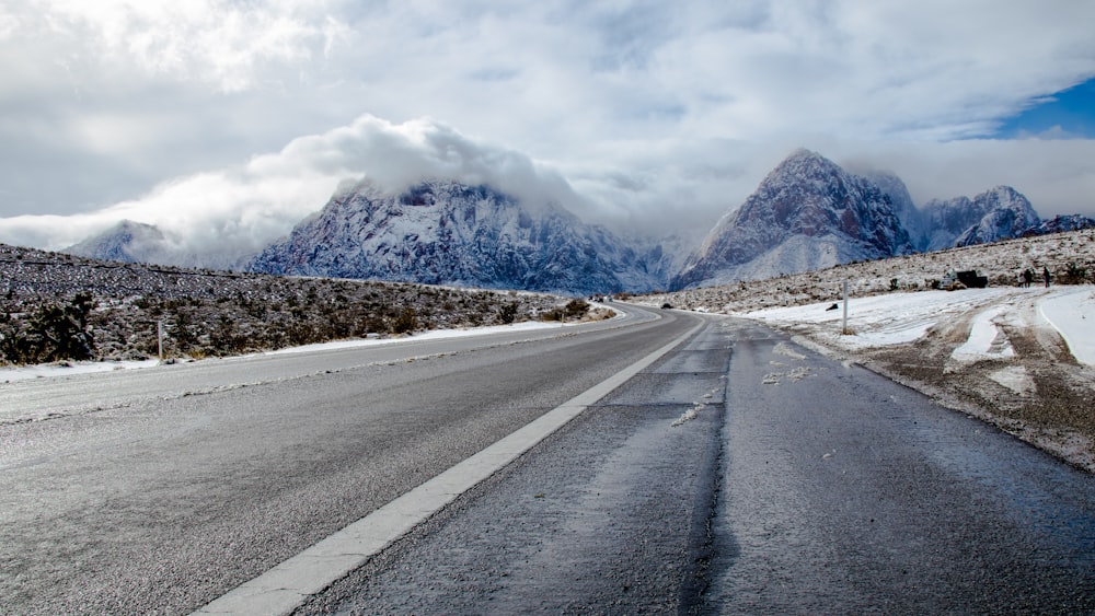 gray concrete road near snow covered mountain during daytime