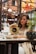 A thoughtful woman reading 'Trust No One' at a café.