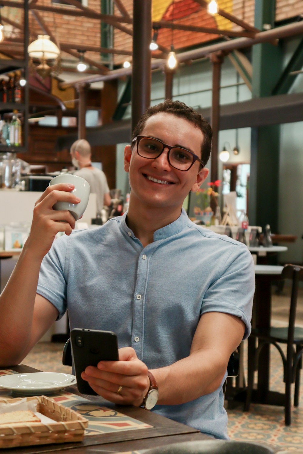 man in blue button up shirt holding white ceramic mug