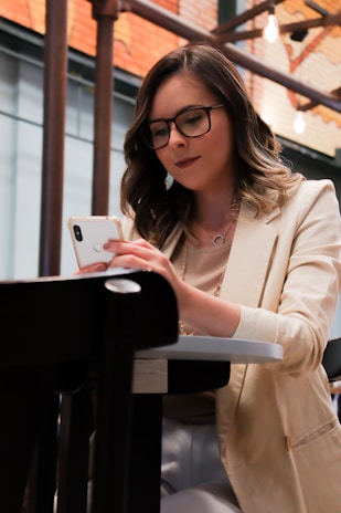 woman in white blazer holding iphone