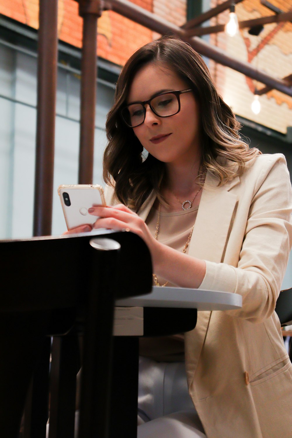 woman in white blazer holding iphone