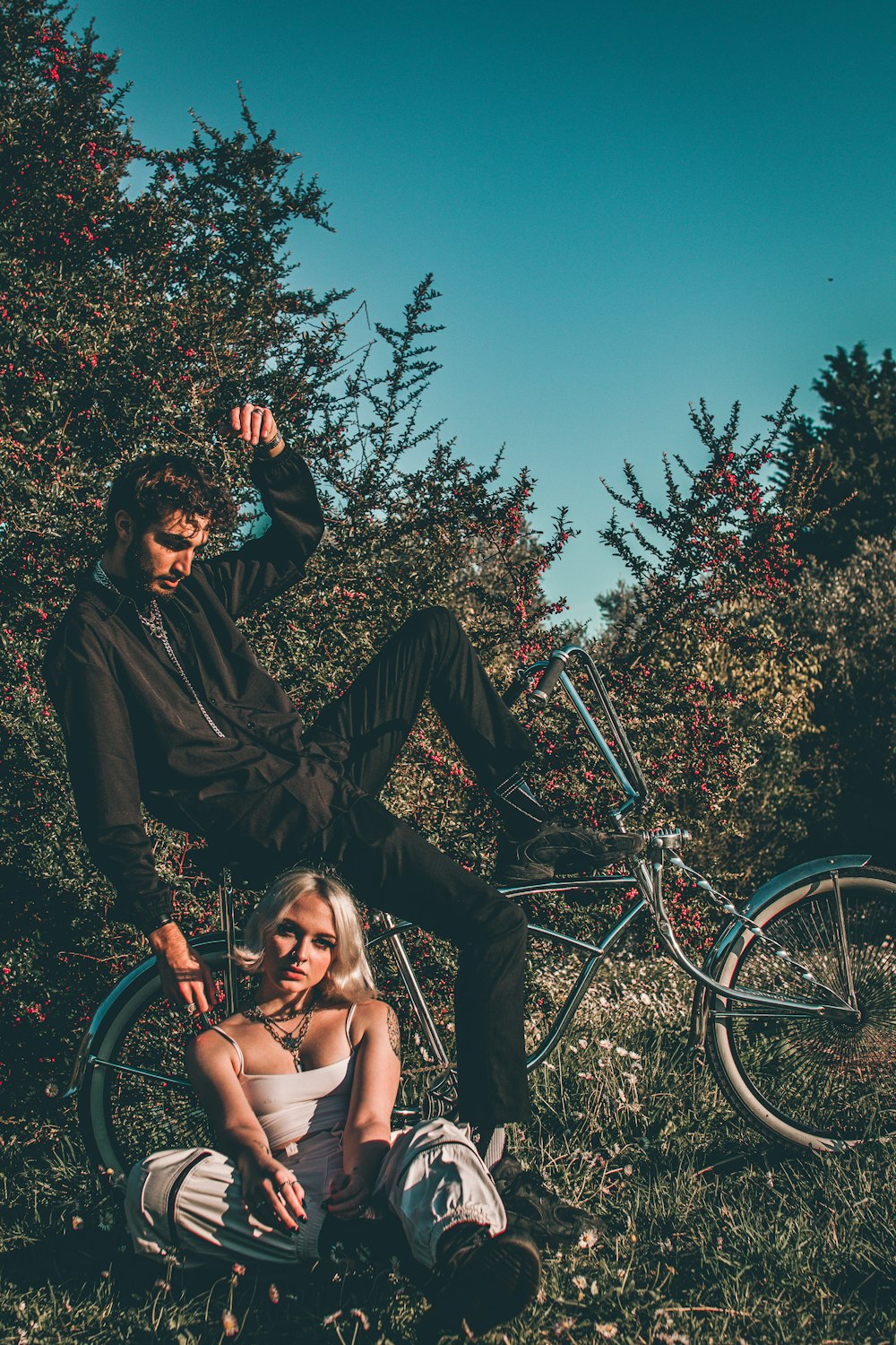 Mann und Frau sitzen tagsüber auf schwarzem Metallrahmen in der Nähe eines grünen Fahrrads