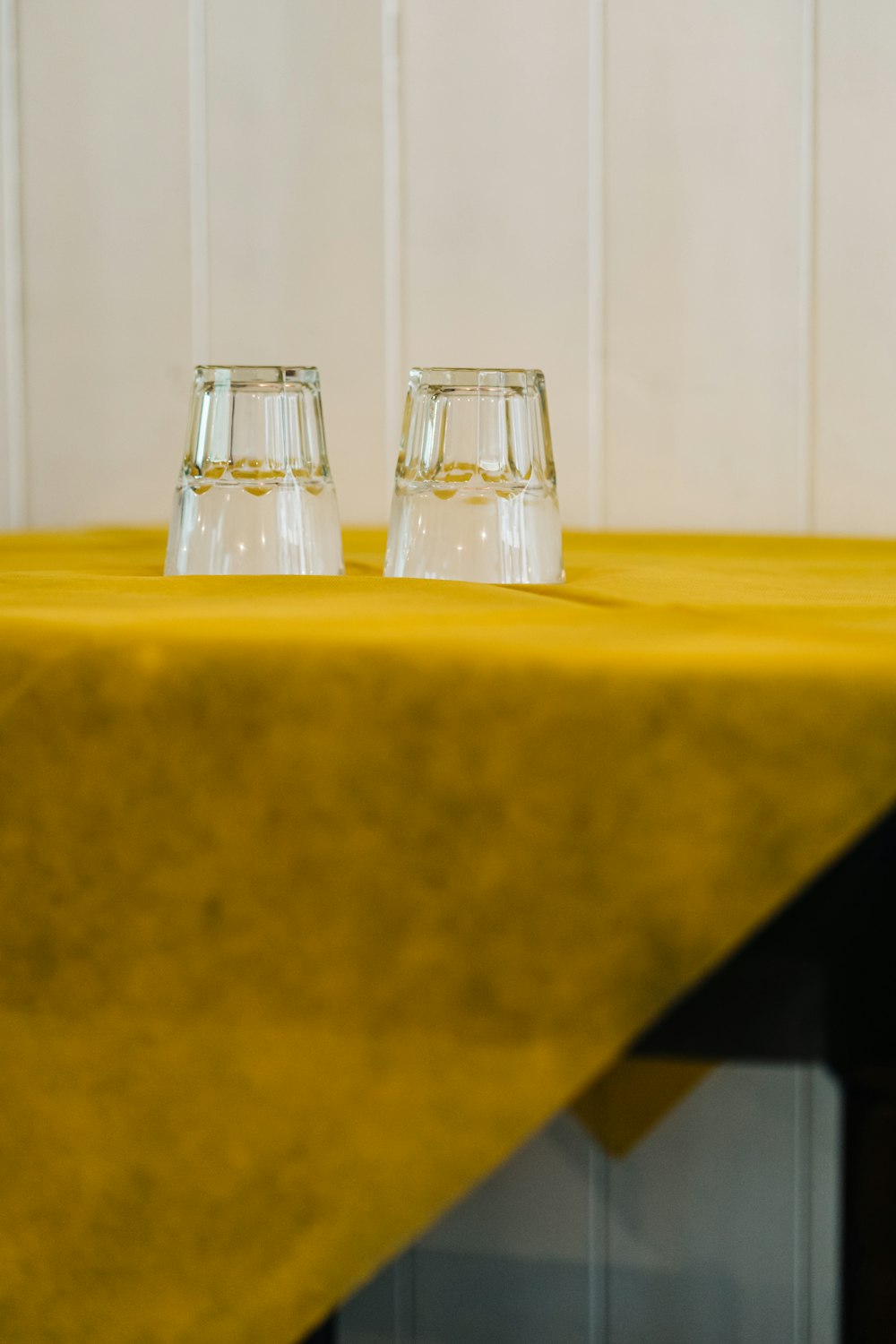 2 clear glass condiment shakers on yellow table