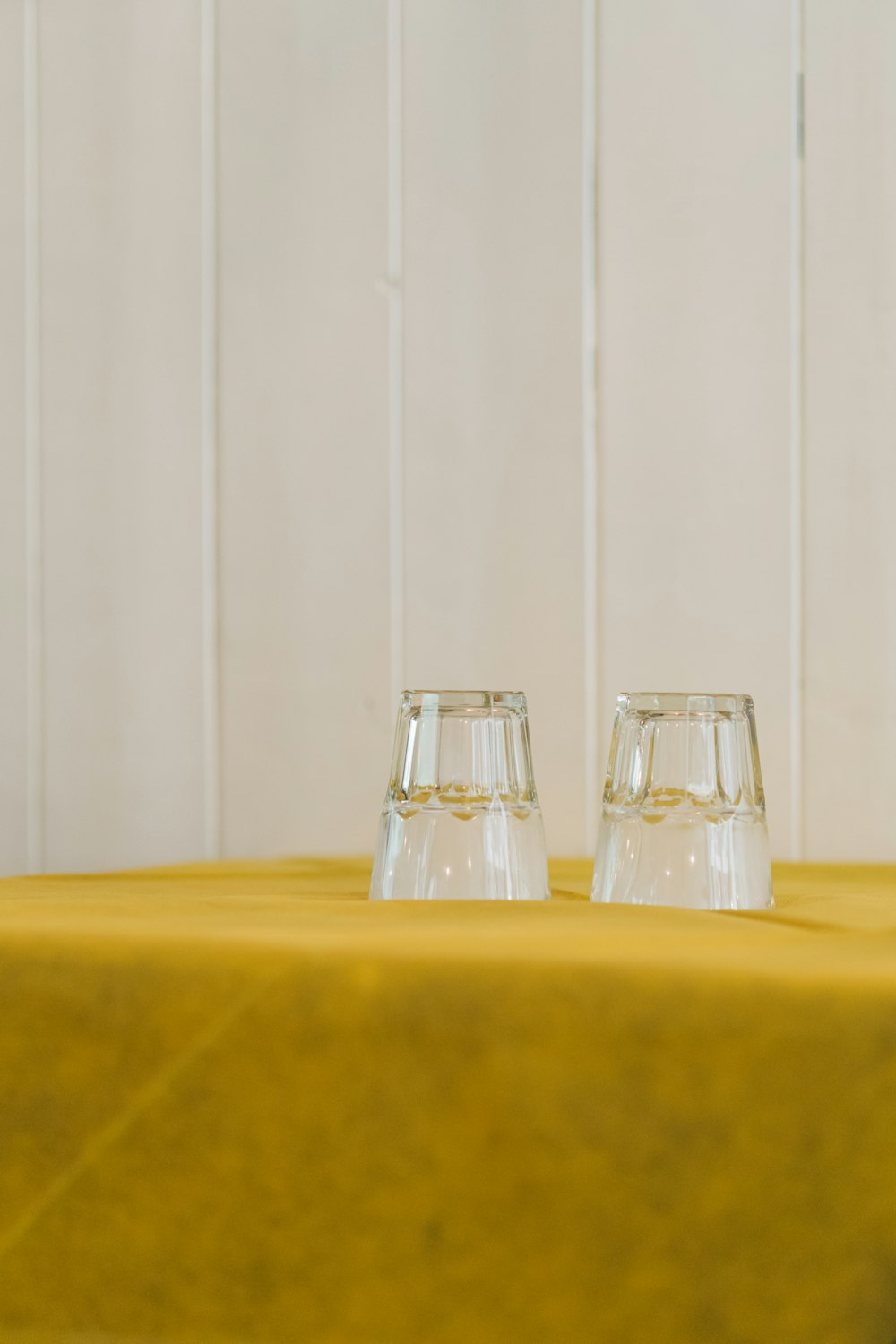 2 garrafas de vidro transparente na mesa amarela