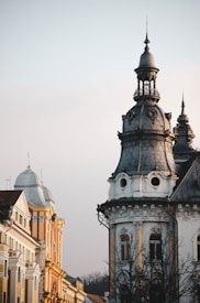 A detailed view of ornate historic buildings with intricate architectural features, including towers and elaborate facades. The structures appear to be from a bygone era, showcasing rich architectural styles.