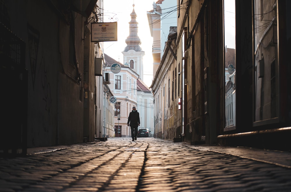 man in black jacket walking on street during daytime