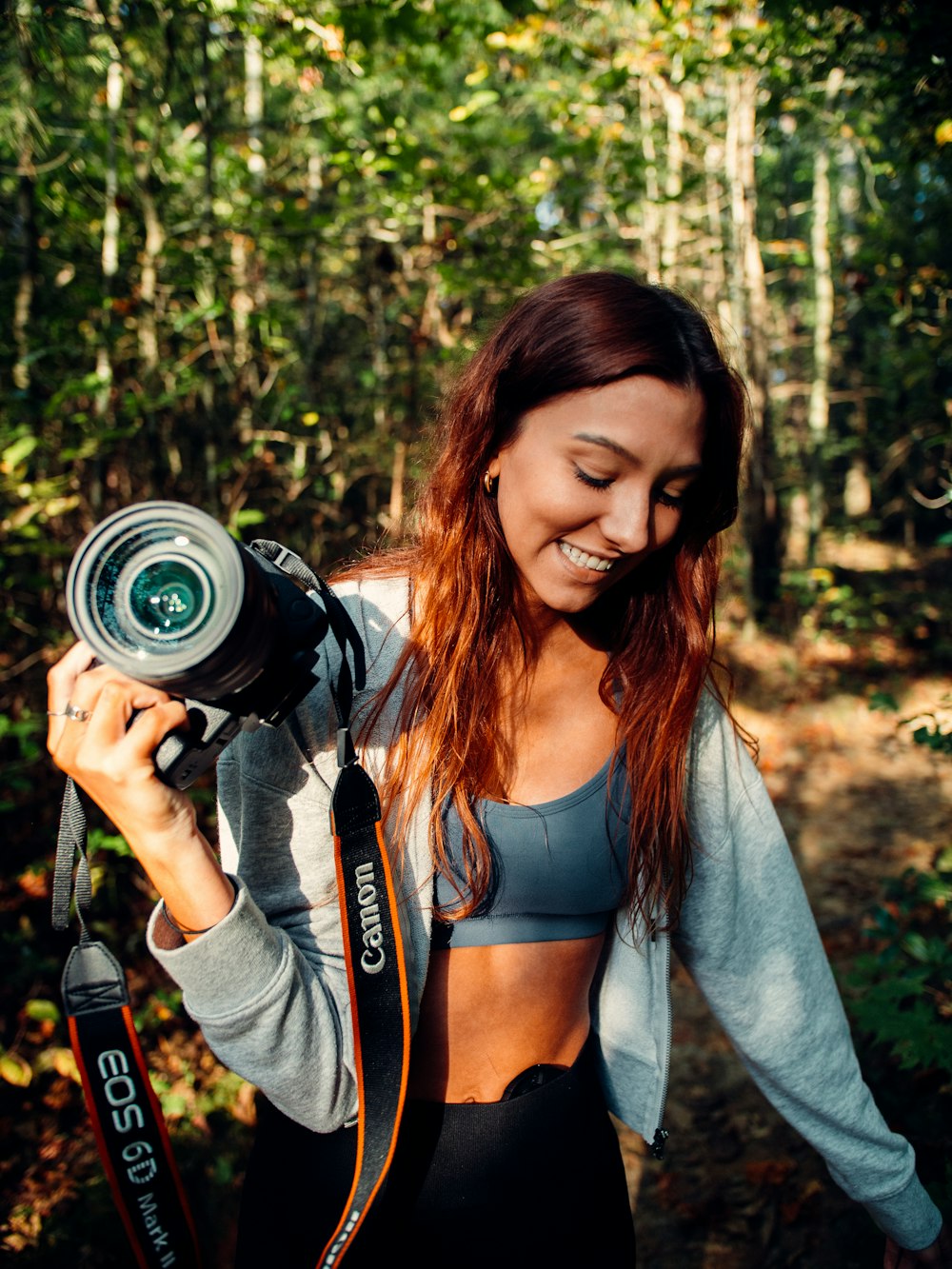 Femme en cardigan gris tenant un appareil photo reflex numérique Nikon noir