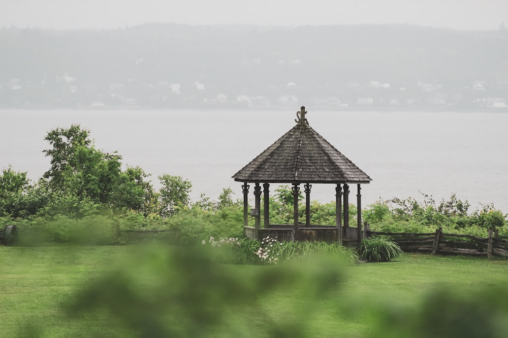 belvédère en bois noir sur un champ d’herbe verte près du plan d’eau pendant la journée