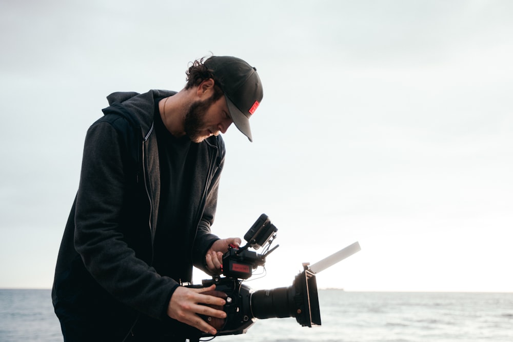 man in black jacket holding black dslr camera