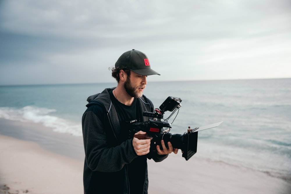 Mann in schwarzer Jacke mit schwarzer DSLR-Kamera