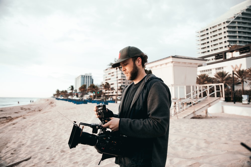 Mann in schwarzer Jacke mit schwarzer DSLR-Kamera