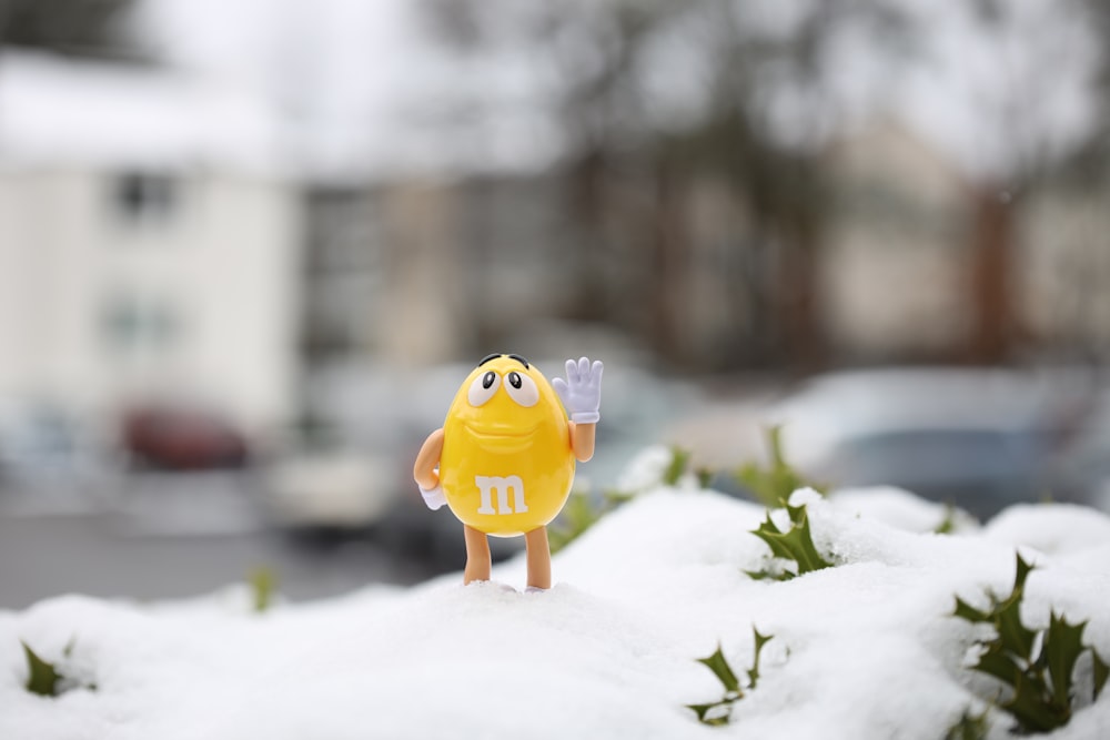 brinquedo plástico do pássaro amarelo no chão coberto de neve