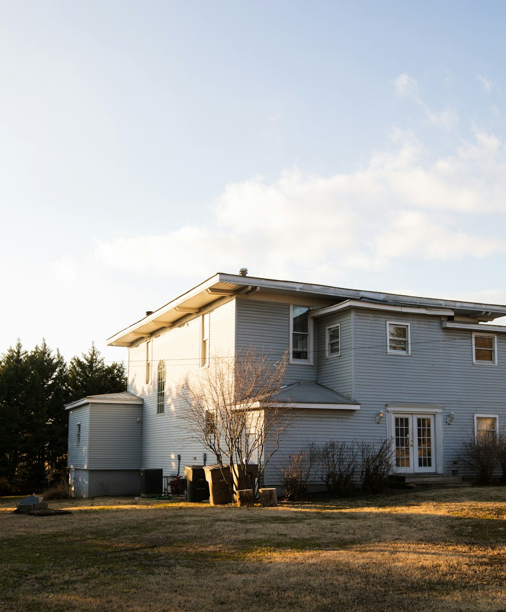 white and gray house near green trees under white sky during daytime