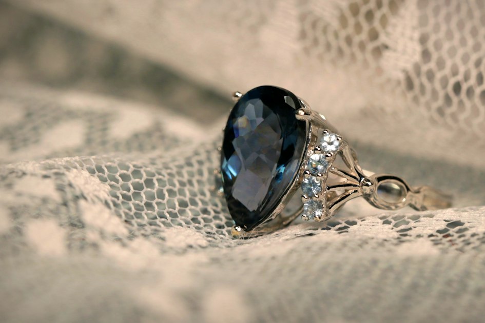A silver ring set with a large blue topaz gemstone, showing the stone's deep blue color