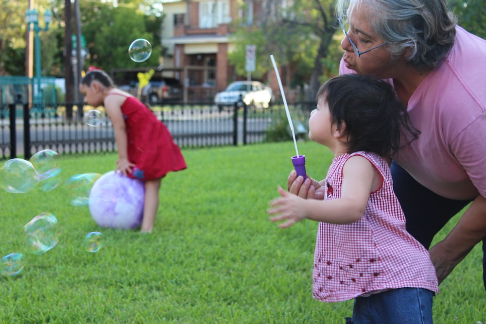 girl in pink and white plaid shirt playing with bubbles during daytime