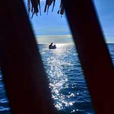A serene image of a small boat steadily rising on gentle waves under a bright sky, symbolizing resilience and upward momentum.