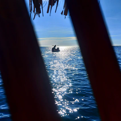 A serene image of a small boat steadily rising on gentle waves under a bright sky, symbolizing resilience and upward momentum.