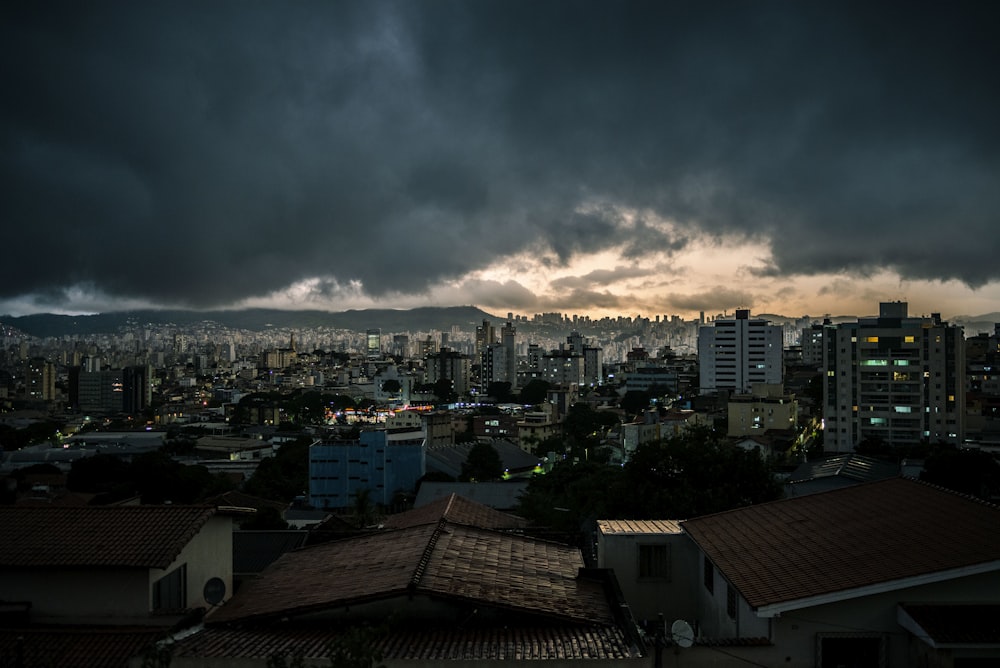 city with high rise buildings under gray clouds during night time