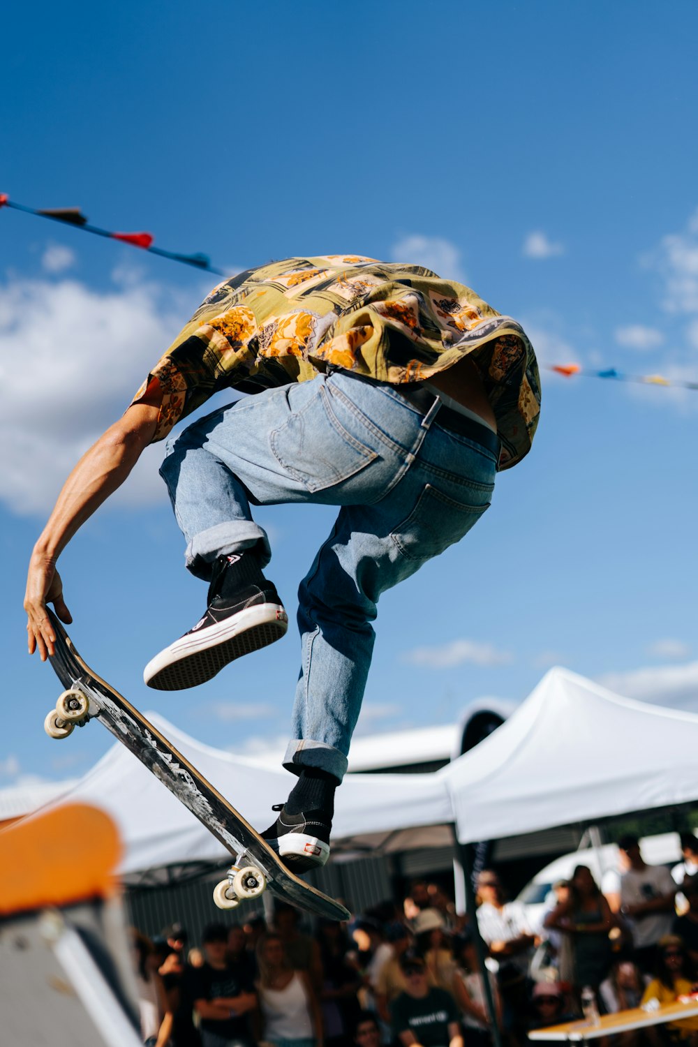 Mann in blauen Jeans und brauner Jacke fährt tagsüber Skateboard