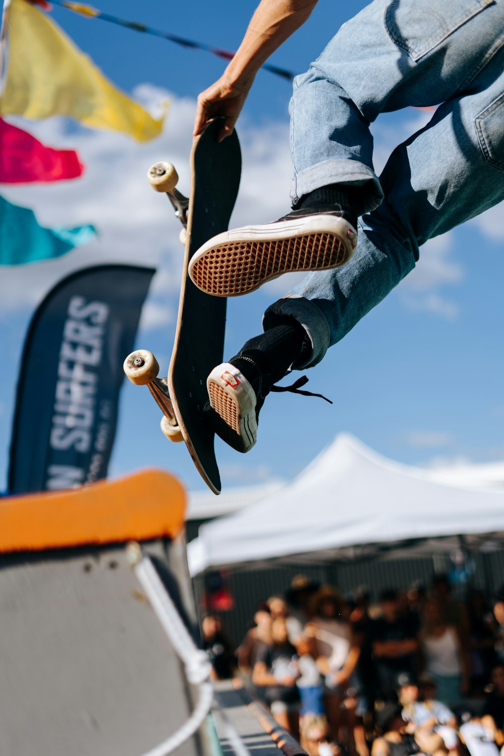 pessoa em jeans azul e tênis preto e branco pulando em metal laranja e branco