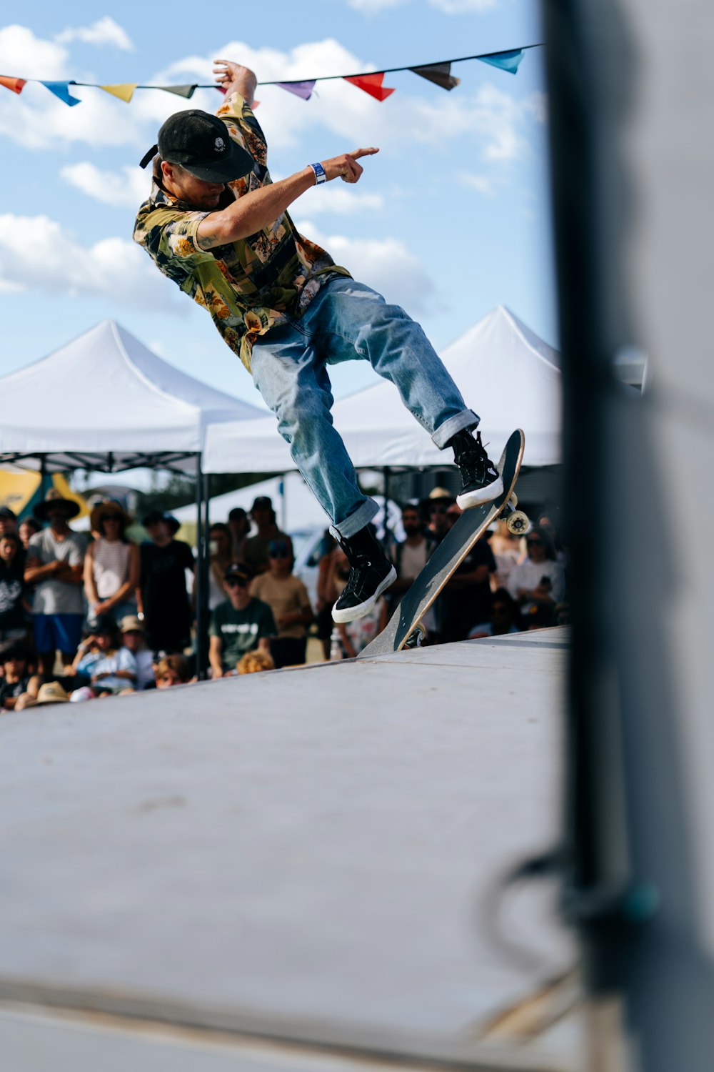 man in green t-shirt and blue denim jeans jumping on skateboard during daytime