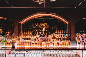 Well-stocked bar with illuminated liquor shelves and seating area