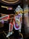 A brightly lit neon sign of a cowgirl wearing a white hat, boots, and a red, white, and blue outfit. The figure is sitting with one leg raised and crossed, in a lively and colorful style, suggestive of a vintage or retro aesthetic.
