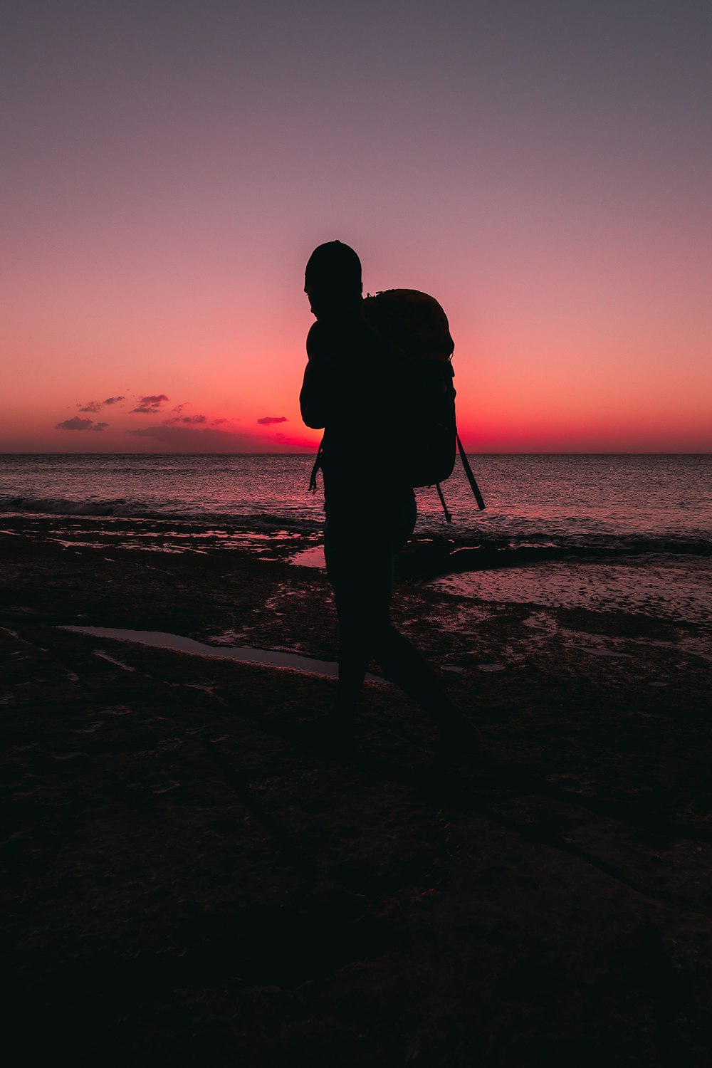 silhouette of man standing on beach during sunset