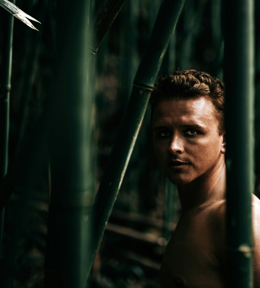 topless man standing near bamboo tree