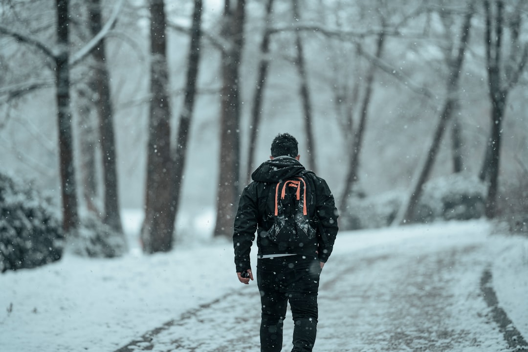 man in black jacket walking on snow covered ground during daytime