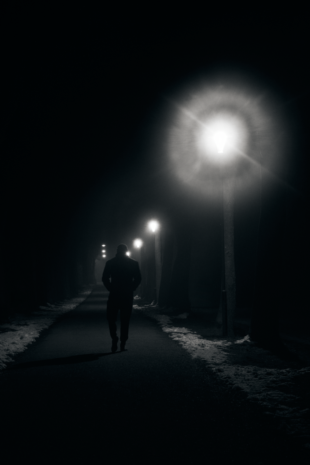 silhouette of man walking on road during night time