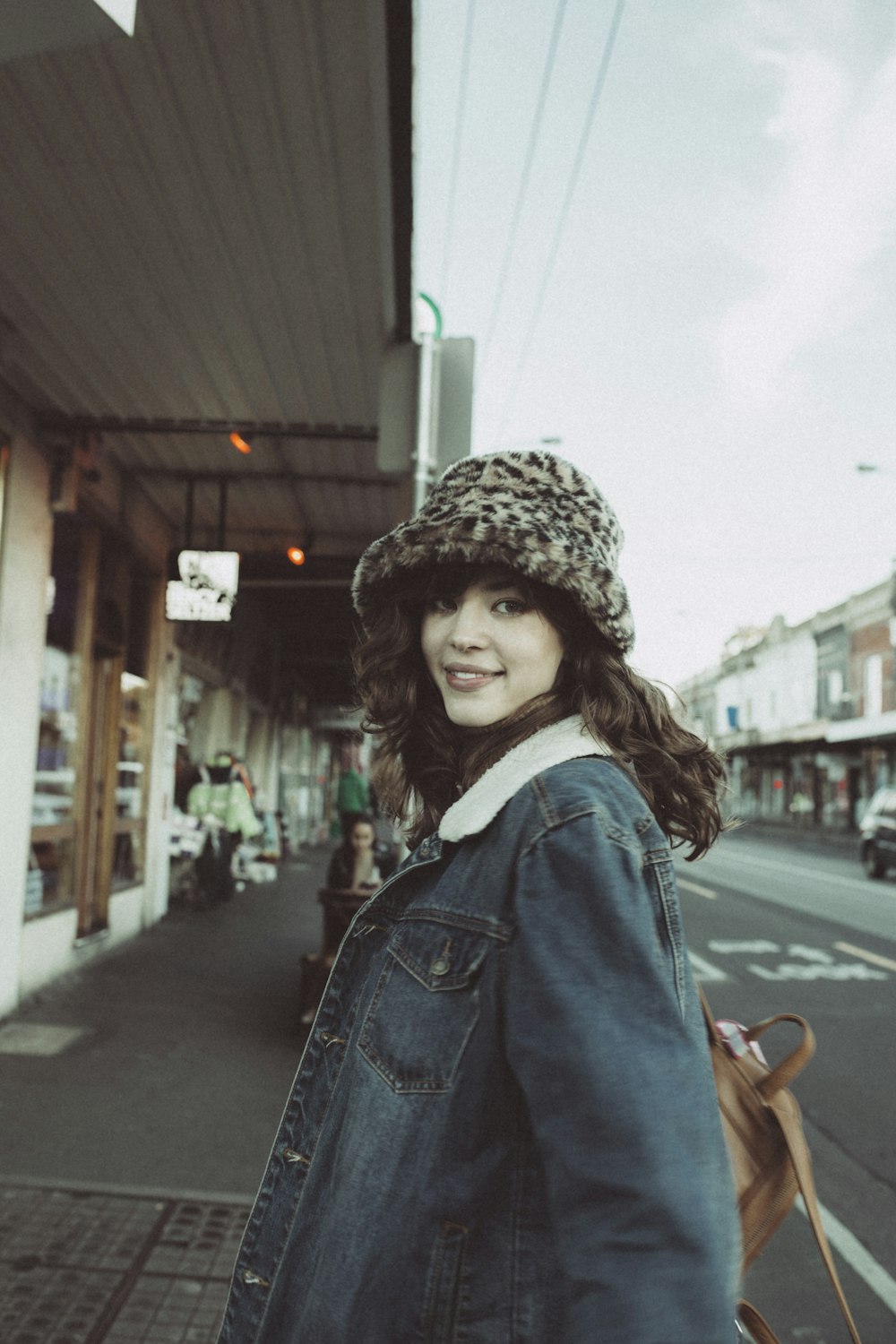 woman in blue denim jacket standing on sidewalk during daytime