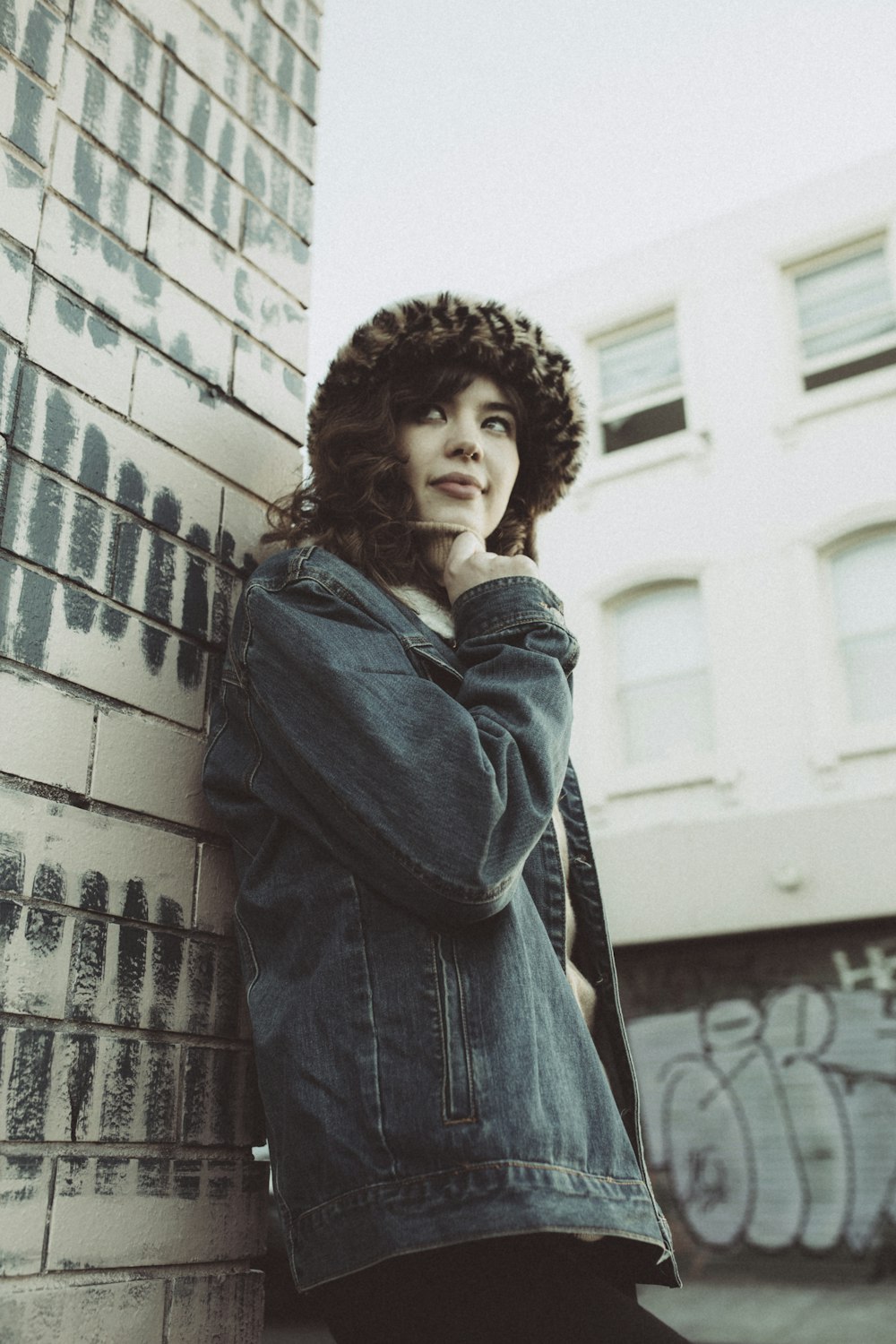 woman in blue denim jacket standing near white concrete building during daytime