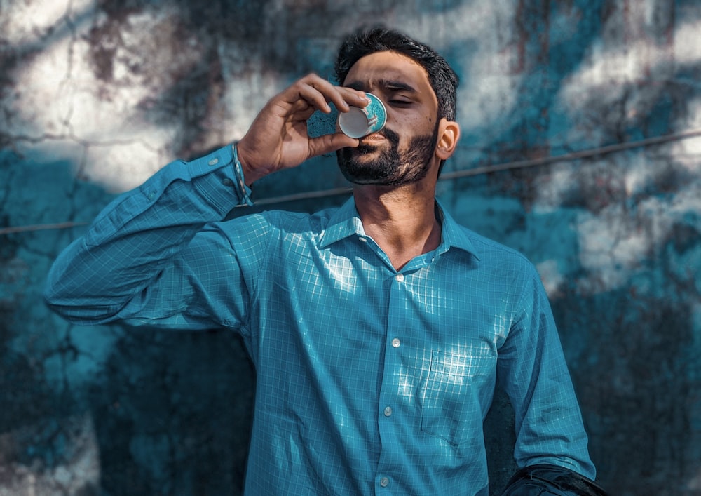 man in blue dress shirt drinking from bottle