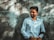 man in blue dress shirt standing beside gray wall