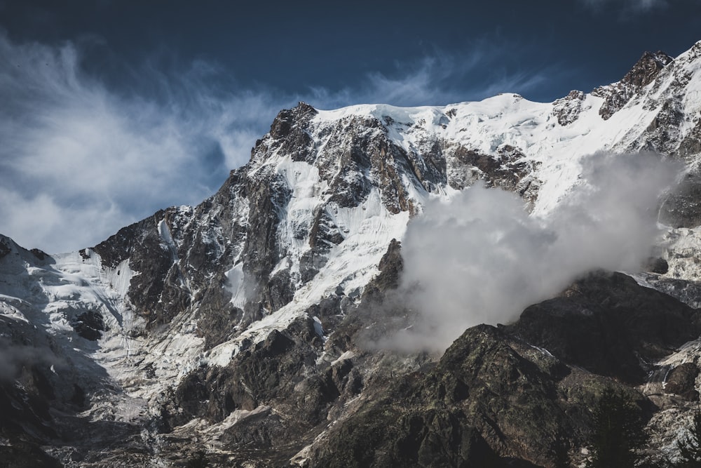 a mountain covered in snow under a cloudy sky