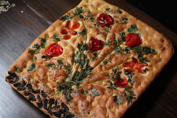 A freshly baked focaccia topped with herbs and olive oil.