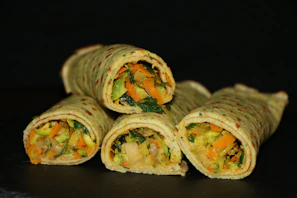 A close-up of colorful vegetable wraps with fresh herbs and light dressing.