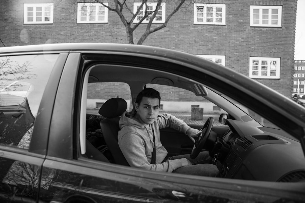 man in gray jacket sitting on car seat